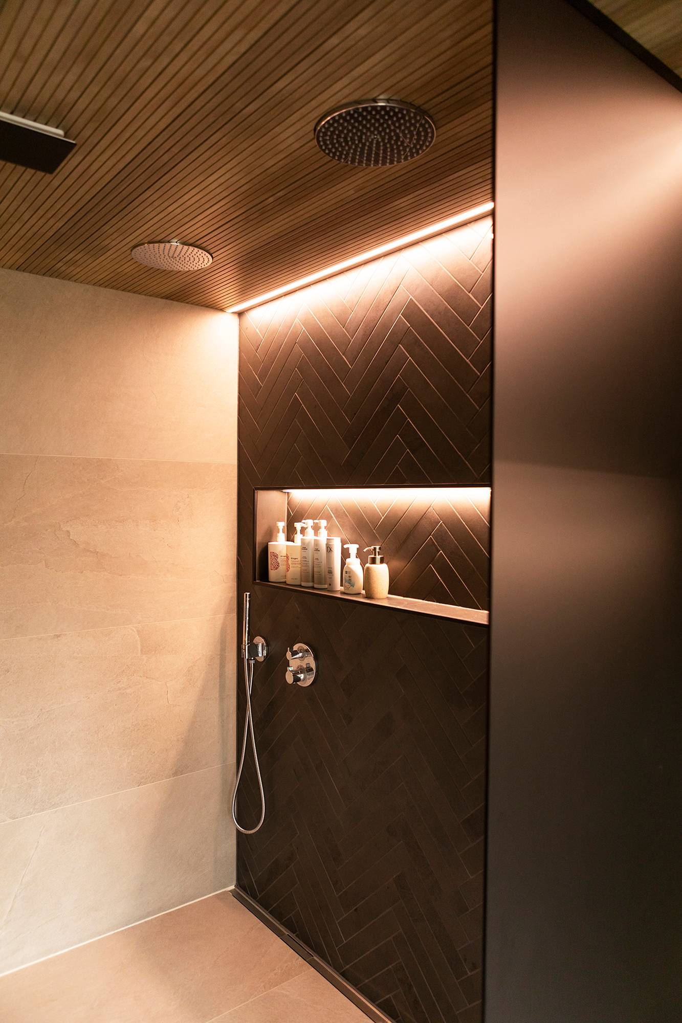 Un estante para champú y una tira de leds junto a la pared crean una luz de acento indirecta. Tira de leds en el perfil empotrado. Ledstore.fi